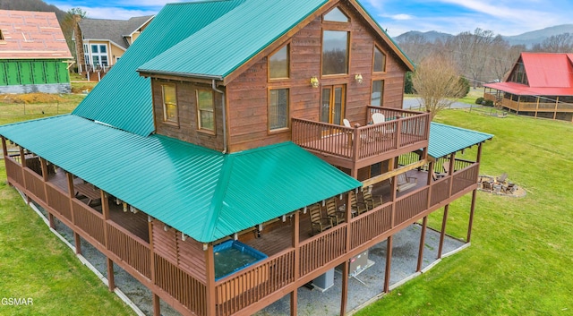 rear view of house with a deck with mountain view, a lawn, and metal roof