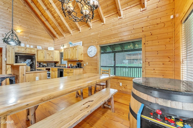 dining space with high vaulted ceiling, light wood-style flooring, an inviting chandelier, wood walls, and wooden ceiling