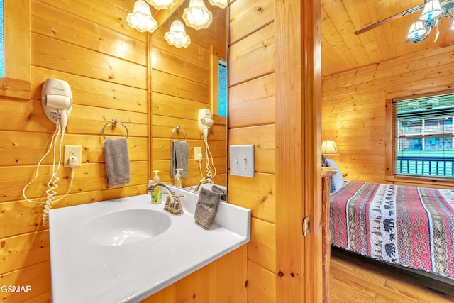 bathroom with wood walls, wooden ceiling, vanity, and wood finished floors