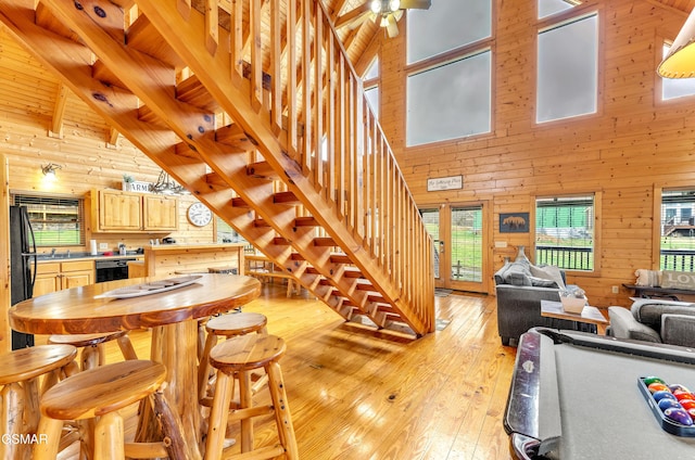 interior space featuring stairs, wooden walls, beamed ceiling, and light wood finished floors