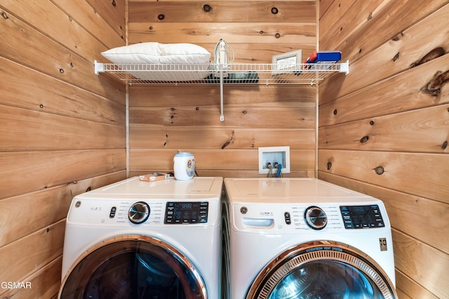 laundry area featuring separate washer and dryer and wood walls