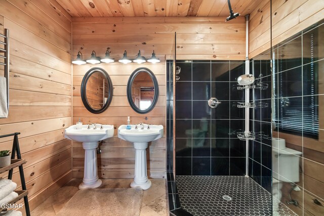 bathroom featuring wood walls, double sink, tiled shower, and wooden ceiling