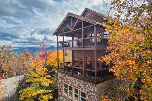 rear view of property with a mountain view and a balcony