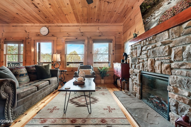 living room with a stone fireplace, wooden ceiling, and wooden walls