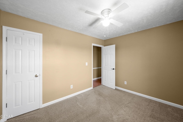 unfurnished bedroom with a textured ceiling, carpet, a ceiling fan, and baseboards