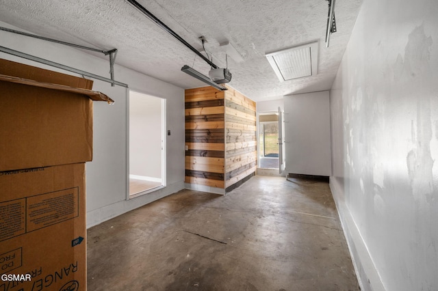 garage featuring a garage door opener, wooden walls, and baseboards