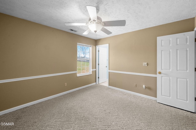 spare room featuring carpet, visible vents, a textured ceiling, and baseboards