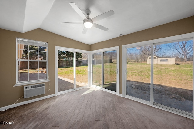 unfurnished sunroom featuring lofted ceiling, plenty of natural light, a ceiling fan, and an AC wall unit