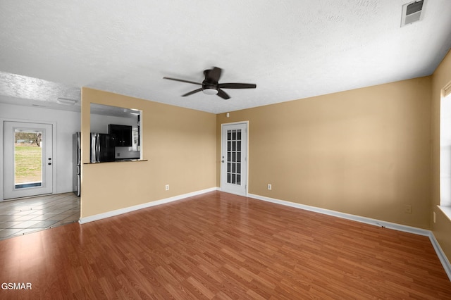 spare room with a textured ceiling, baseboards, and wood finished floors