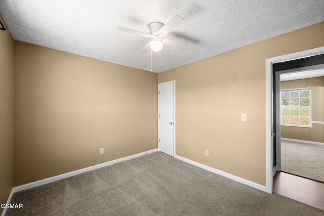 empty room featuring a textured ceiling, carpet floors, a ceiling fan, and baseboards