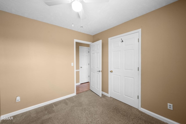 unfurnished bedroom with a textured ceiling, carpet flooring, a ceiling fan, and baseboards