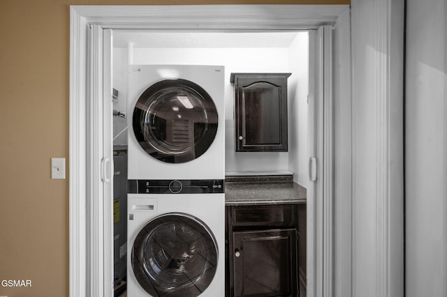 laundry area with stacked washer and dryer and cabinet space