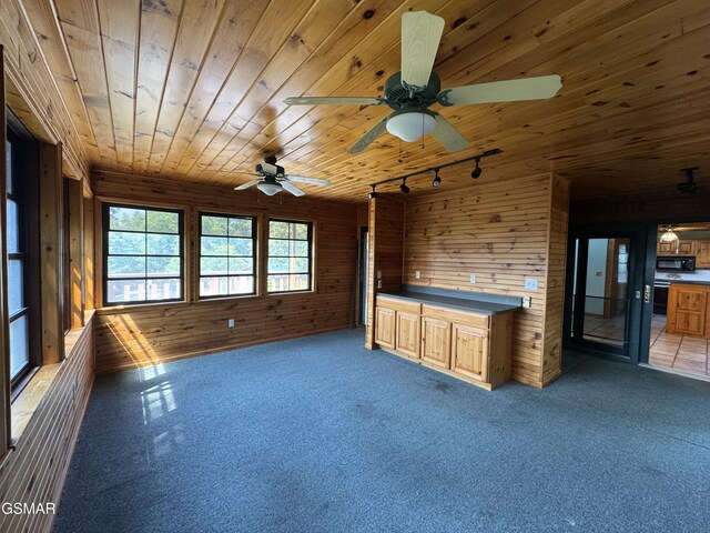 2452 Skyview Way, Dandridge, TN 37725 - unfurnished living room featuring wooden walls, track lighting, wooden ceiling, ceiling fan, and dark carpet