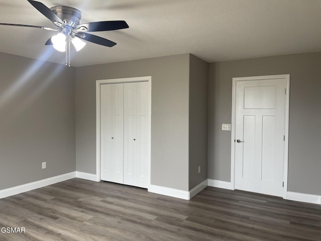 unfurnished bedroom with a closet, dark hardwood / wood-style floors, and ceiling fan