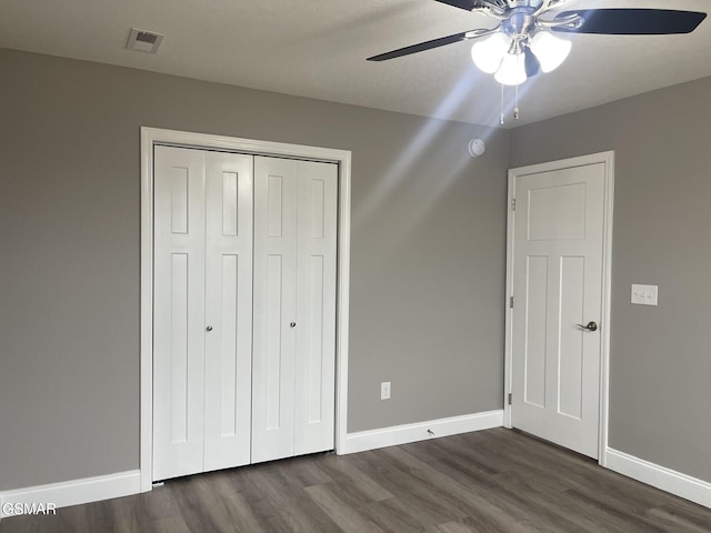 unfurnished bedroom featuring dark wood-type flooring, ceiling fan, and a closet