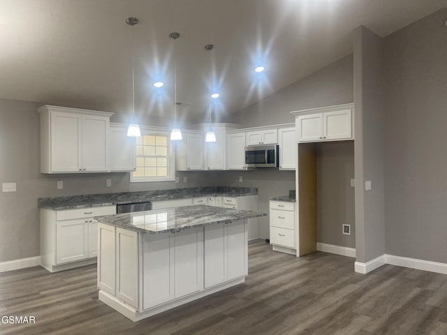 kitchen with light stone counters, a center island, dark hardwood / wood-style floors, stainless steel appliances, and white cabinets