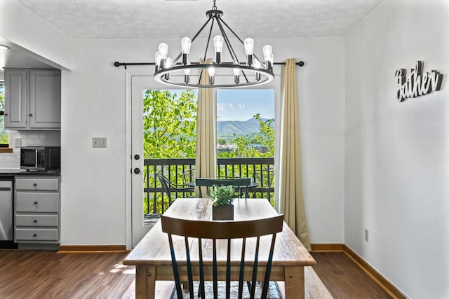 dining area with a textured ceiling, a notable chandelier, and dark hardwood / wood-style flooring