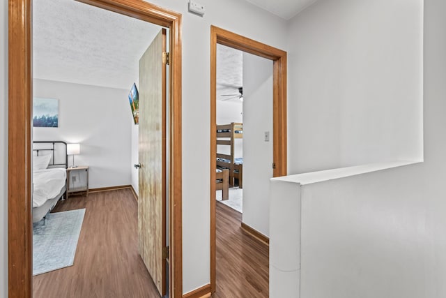 hall with hardwood / wood-style floors and a textured ceiling