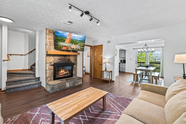 living room with a fireplace, rail lighting, dark wood-type flooring, and a textured ceiling