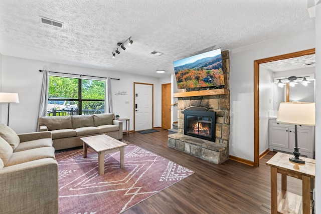 living room featuring a fireplace, rail lighting, a textured ceiling, and dark hardwood / wood-style flooring