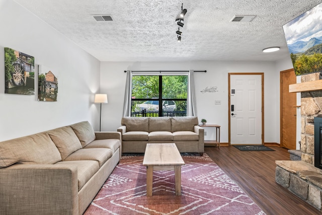 living room featuring a textured ceiling, dark hardwood / wood-style floors, and a stone fireplace