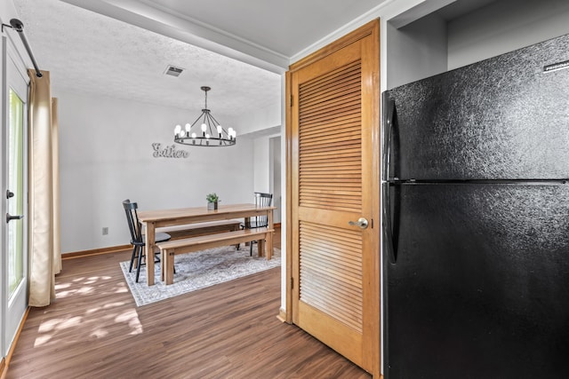 dining room featuring an inviting chandelier, a textured ceiling, and dark hardwood / wood-style flooring