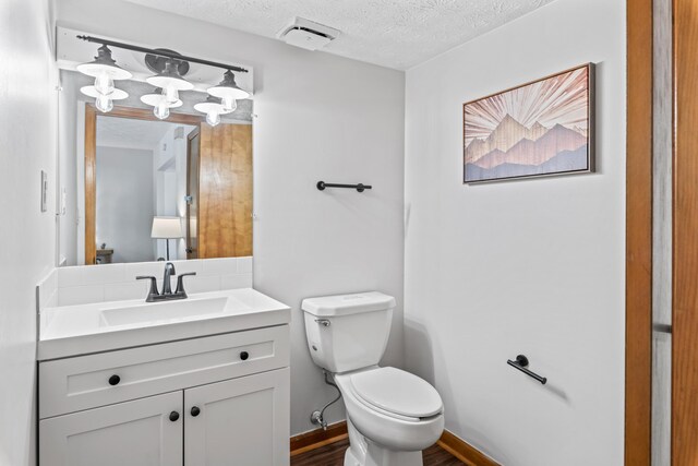 bathroom featuring toilet, a textured ceiling, and vanity