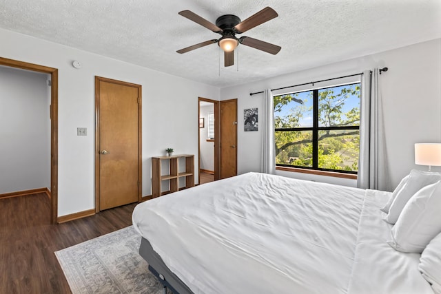 bedroom with a textured ceiling, dark hardwood / wood-style floors, and ceiling fan