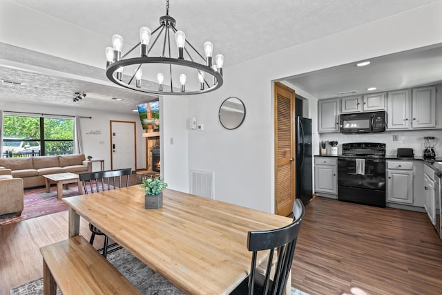 dining space featuring a textured ceiling, dark hardwood / wood-style flooring, and an inviting chandelier