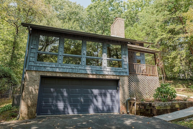 view of front of property featuring a garage, brick siding, driveway, and a chimney