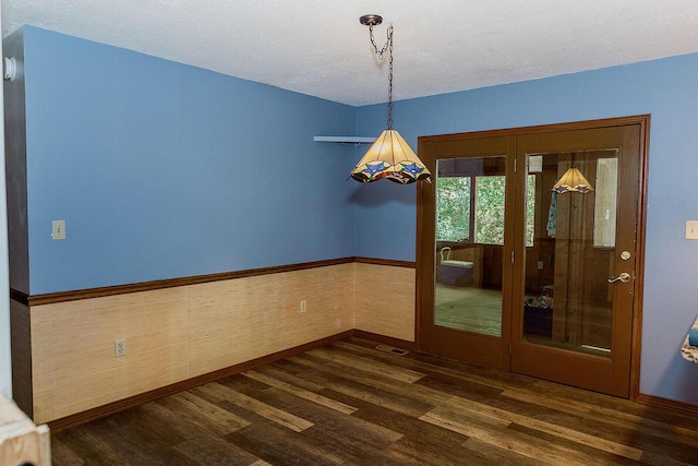 unfurnished dining area featuring wainscoting, visible vents, and dark wood finished floors