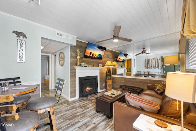 685 River Rd Unit 411, Gatlinburg, TN 37738 - living room featuring wood finished floors, wooden walls, a ceiling fan, a warm lit fireplace, and baseboards