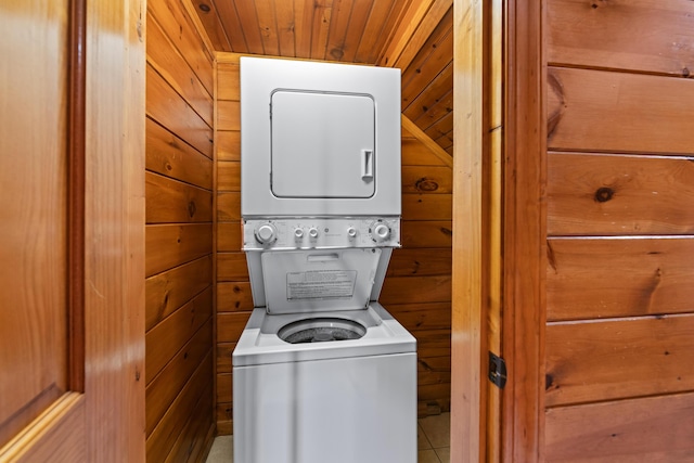 washroom featuring wood walls, stacked washing maching and dryer, and wood ceiling