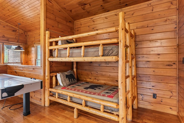 bedroom with hardwood / wood-style floors, wood walls, wooden ceiling, and vaulted ceiling