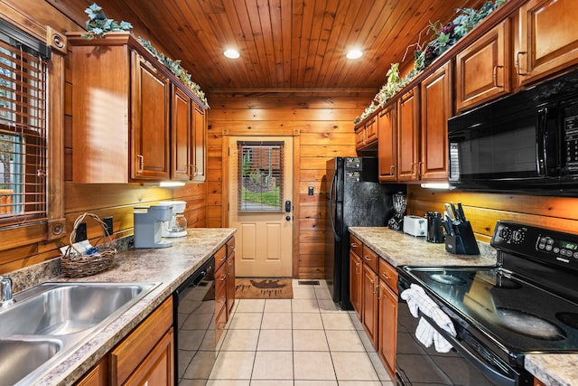 kitchen featuring wooden walls, sink, light tile patterned floors, and black appliances