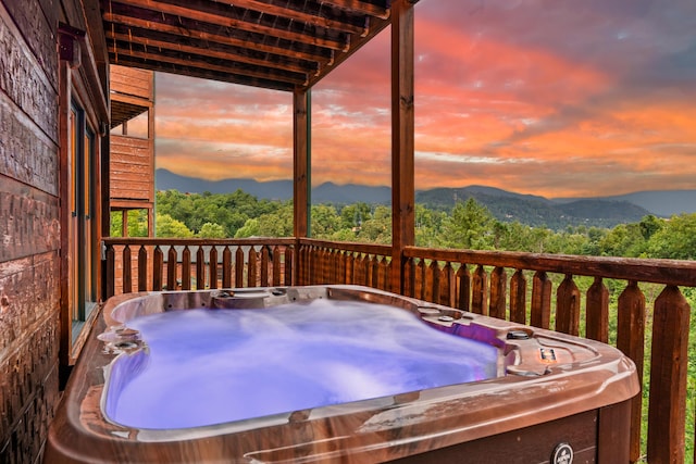 deck at dusk with a mountain view and a hot tub