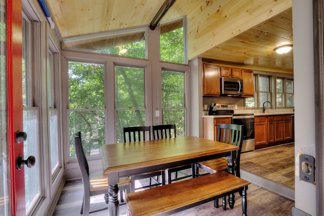 dining area with light hardwood / wood-style floors, lofted ceiling, sink, and wooden ceiling