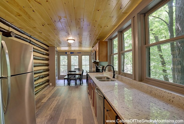 kitchen with appliances with stainless steel finishes, light stone counters, wood ceiling, sink, and dark hardwood / wood-style floors