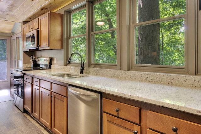 kitchen with light stone countertops, sink, stainless steel appliances, light hardwood / wood-style flooring, and wood ceiling