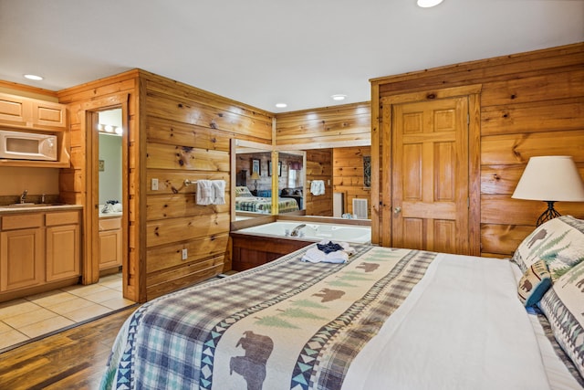 bedroom with sink, light wood-type flooring, and wood walls