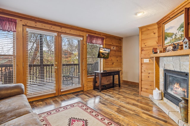 living room featuring a wealth of natural light, a fireplace, wooden walls, and wood-type flooring