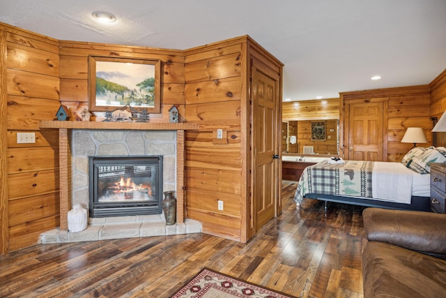 bedroom featuring dark wood-type flooring, wooden walls, and a fireplace