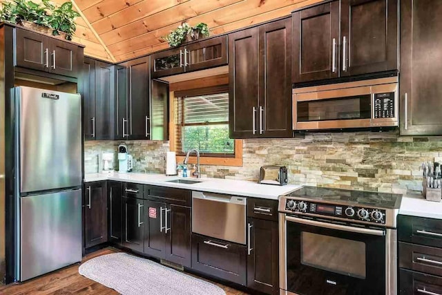 kitchen with sink, lofted ceiling, dark brown cabinets, wood ceiling, and appliances with stainless steel finishes