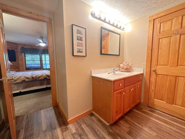 bathroom with ceiling fan, vanity, wood-type flooring, and a textured ceiling