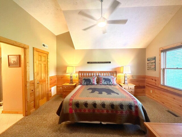 carpeted bedroom with ceiling fan, lofted ceiling, a textured ceiling, and wooden walls