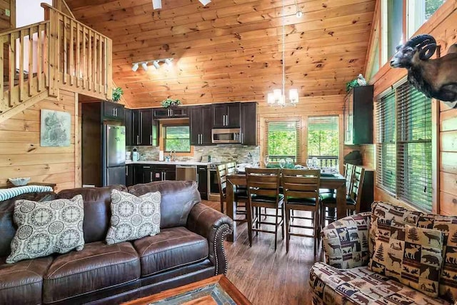 living room featuring sink, high vaulted ceiling, dark hardwood / wood-style floors, a notable chandelier, and wood walls