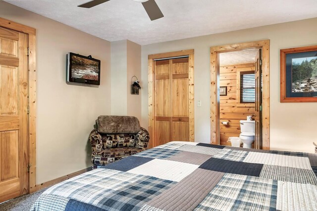 carpeted bedroom with wooden walls, ceiling fan, a textured ceiling, connected bathroom, and a closet