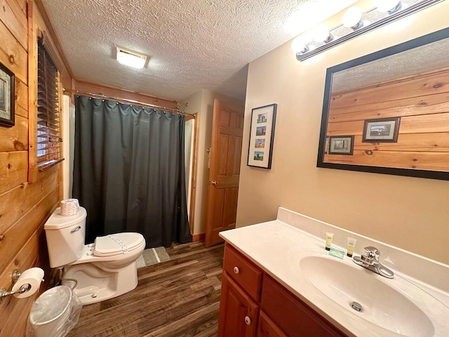 bathroom with a shower with shower curtain, vanity, a textured ceiling, wood-type flooring, and toilet