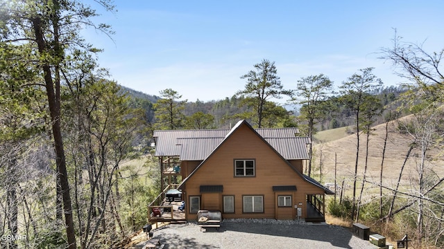 rear view of property featuring a forest view and metal roof