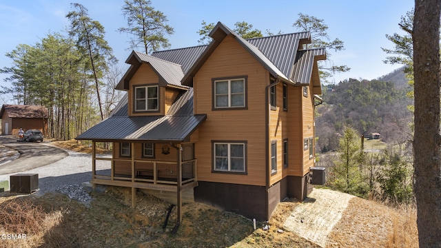 view of front facade with metal roof, central AC, and driveway